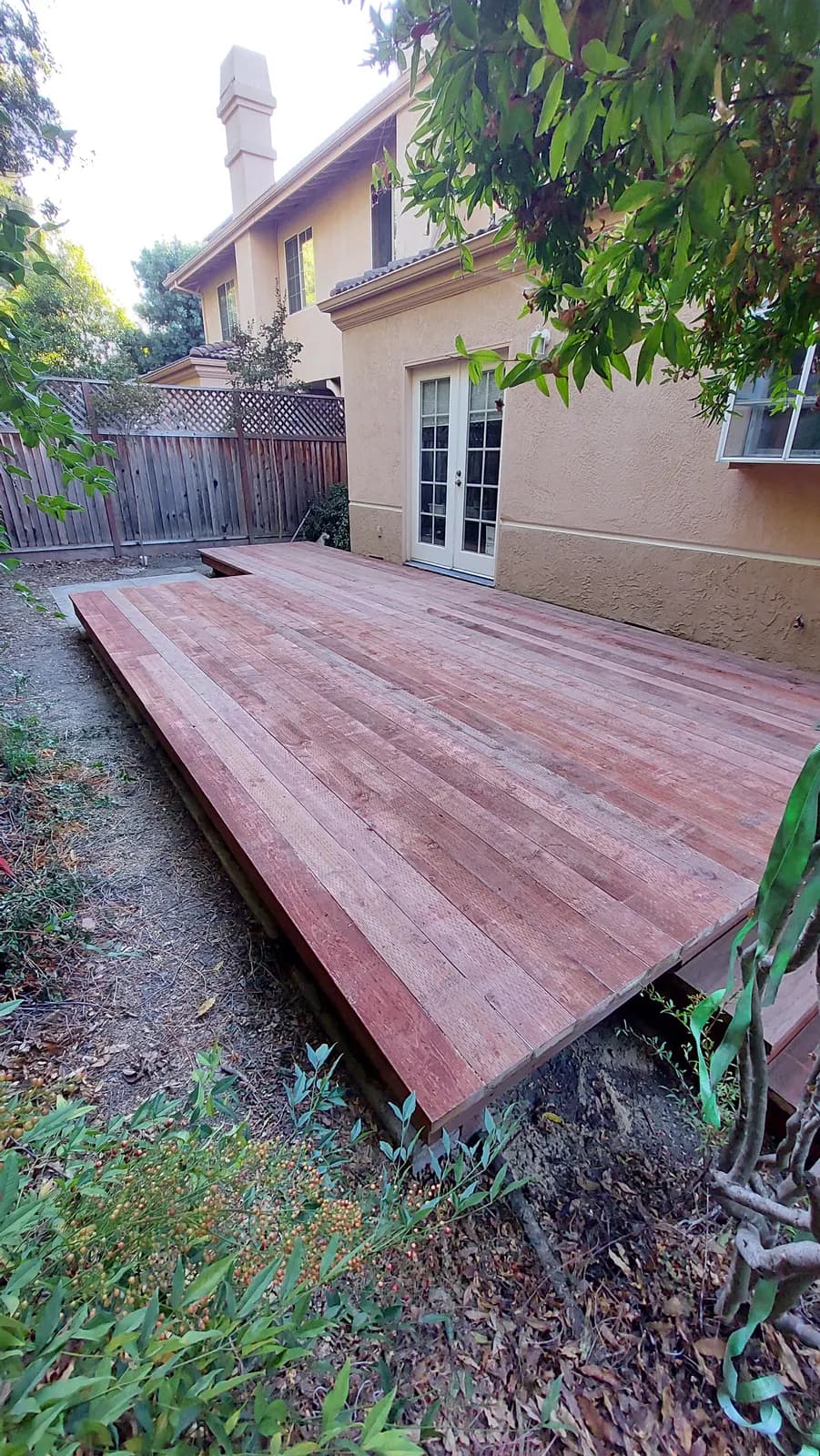 Wider view of the same deck platform from its corner, two-storey stucco house behind and a stepped front edge