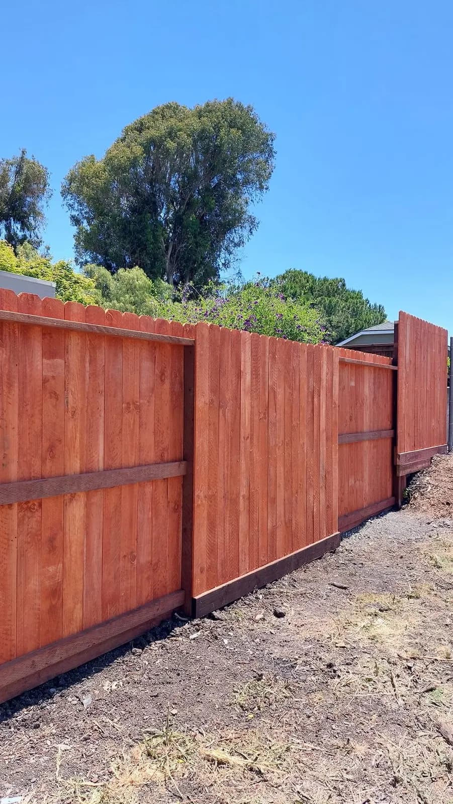Dog-eared redwood fence running downhill, each section stepping lower than the one before it
