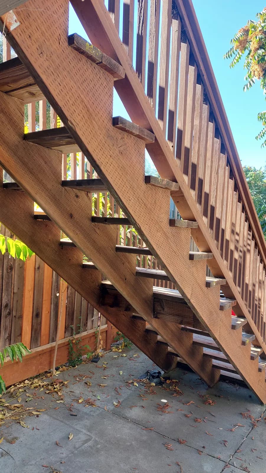Close view along a deck stair stringer with every tread removed, bare notches and cleats exposed